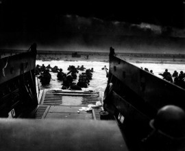 Soldados estadounidenses desembarcan de un bote de la Guardia Costera en las costas de Francia bajo intenso fuego de ametralladoras alemanas durante el “Día-D” el 6 de junio de 1944. (Administración de los Archivos Nacionales)