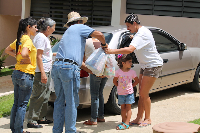 Miembros del Banco de Alimento de Puerto Rico hacen entrega de unas bolsas con alimentos a una comunidad orocoveña. (Michelle Estades)