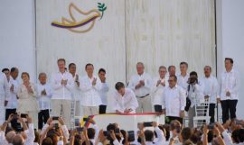 El presidente de Colombia, Juan Manuel Santos, firma el Acuerdo Final de paz, ante la mirada del jefe de las FARC, Rodrigo Londoño, mandatarios latinoamericanos y otras autoridades, en un acto al aire libre en la ciudad de Cartagena de Indias. Crédito: Presidencia de Colombia