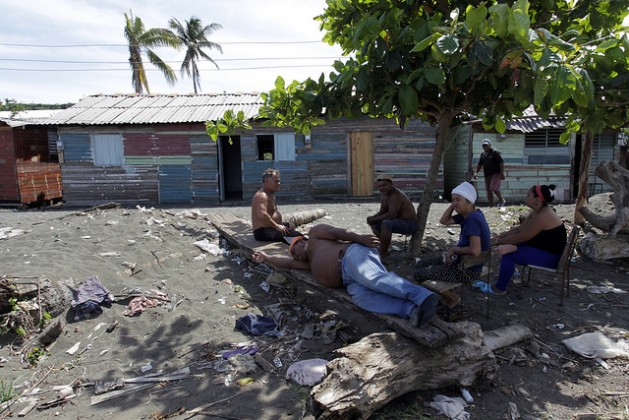 Vecinos de localidad periurbana de La Playa descansan a la sombra de un arbusto, en medio de la contaminada duna formada en la desembocadura del río Macaguaní, llamada localmente tibaracón, próxima a la ciudad de Baracoa, en la costa del oriente de Cuba. Crédito: Jorge Luis Baños/IPS