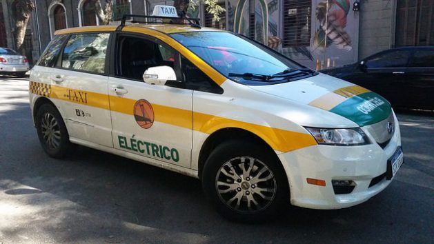 El taxi eléctrico de Alejandro Casas en una calle de Montevideo. El vehículo le costó 63.000 dólares, pero con un crédito a pagar en cinco años y el beneficio de la carga gratis, en una iniciativa apoyada por la empresa eléctrica estatal y la alcaldía de la capital uruguaya. Crédito: Verónica Firme/IPS
