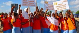 Niñas vestidas con el color naranja de la campaña del activismo para erradicar la violencia hacia las mujeres, se manifiestan en Dar es Salaam, en Tanzania. Un letrero dice: “Absténgase de usar lenguaje ofensivo para mujeres y niñas”. Crédito: Deepika Nath/ONU Mujeres