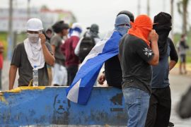 Jóvenes manifestantes nicaragüenses ocultan sus rostros detrás de una barricada en el sur de Managua, levantada con un muro en el que está impresa una imagen del presidente Daniel Ortega. La represión contra las protestas suma ya 131 personas muertas. Crédito: Jader Flores/IPS